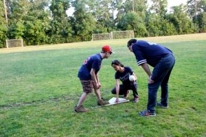 Kara and Ben teach a camper how to set up at the plate