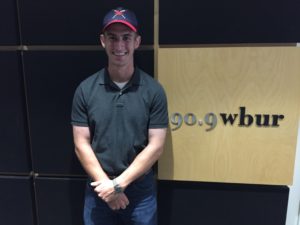 Christian Thaxton stands in front of the WBUR sign