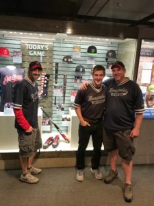 Rob, Christian and Ron stand in front of a case at the Baseball hall of fame where Thaxton's bat is on display