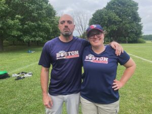 Rob Dias stands next to Gina Devenish with his arm oin her shoulder and a big smile from Gina - buit no smile from Dias