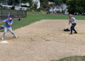 Hunter Weissman delivers a pitch to Rob Dias on a dirt softball field