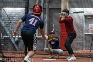Rasik is squated behind the plate as Hunter delivers a pitch against the Northeastern University baseball team
