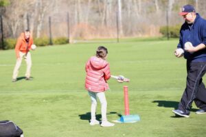 Ron is working with a student off a batting T as she makes contact with the ball